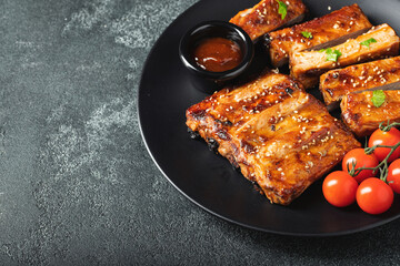 Hot grilled spare ribs from a summer BBQ served on a plate with sauce. Top view. Copy space