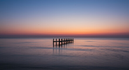 Fototapeta premium Sunset over calm ocean with wooden pier