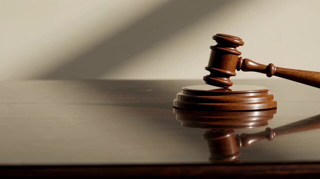 Polished wooden gavel impacts soundblock creating reverberations, symbolizing legal decisions, judgements, and auctions in a courtroom or auction setting