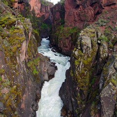 Obraz premium Fast-flowing river through a narrow canyon with red rock walls