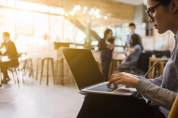 Obraz premium Young entrepreneur working on laptop in coworking space, creative startup atmosphere, modern business background.