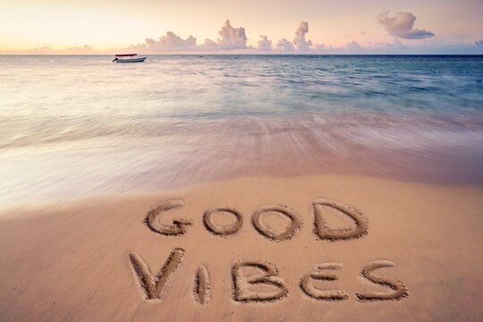 handwritten good vibes on sandy beach at sunset, Dominican republic