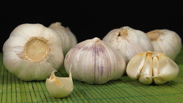 Garlic rotates on dark background. Garlic - vegetable with many beneficial properties for health. Garlic, Allium sativum, species of bulbous flowering plants in genus Allium