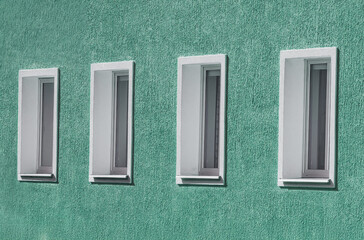 Four Narrow Windows on Teal Stucco Wall