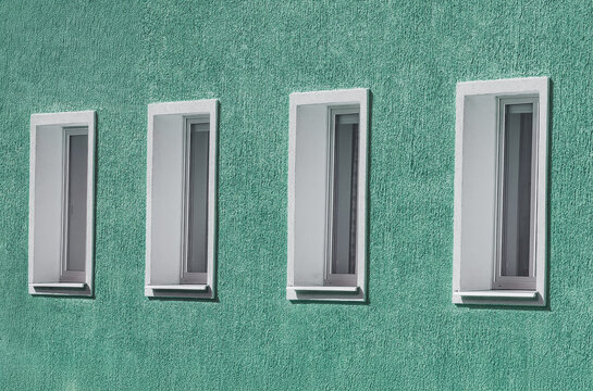 Four Narrow Windows on Teal Stucco Wall