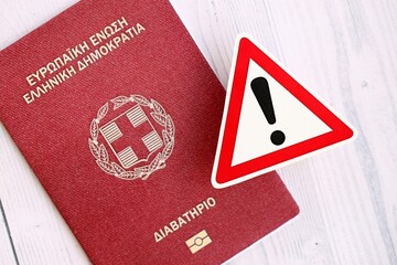 Greece passport with exclamation sign on wooden table. Problems with citizenship in Europe
