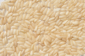 Close up view of uncooked brown rice grains texture with natural organic food pattern.