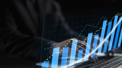 A business professional works on a laptop, analyzing digital graphs that illustrate significant data trends and financial growth in a modern office setting. Copula