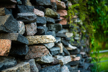 Rough stone wall stacking with overgrown greenery on a side