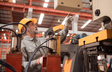 Senior experienced technician checking and maintenance a large machine in metal sheet factory