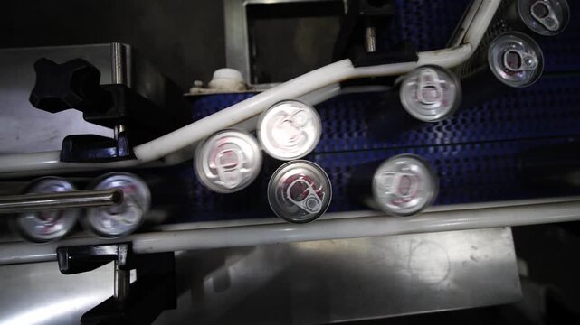 Automated Beverage Can Filling Line: A close-up view of a modern production line showing aluminum cans being filled and sealed on a conveyor belt.