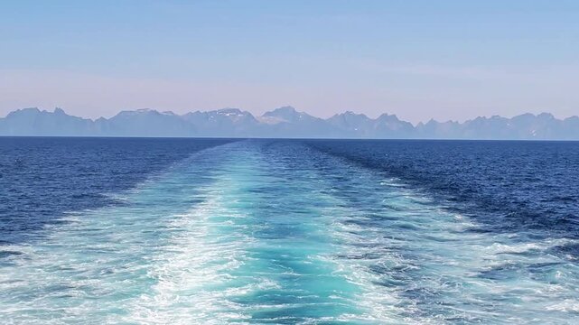 Departure of the ferry from Moskenes, Lofoten Islands, to Bodo, Norway's mainland. The wake of the ferry, with a distant view of the Lofoten mountains. A beautiful holiday destination in the far north