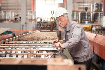 Senior experienced technician checking large machine on a production line