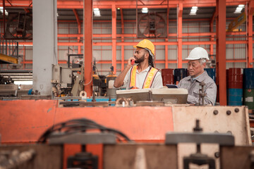 Senior engineers and young man workers are talking and inspecting machines