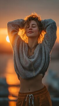 Serene Beauty at Sunset: A young woman basking in the radiant glow of a stunning sunset, her eyes closed in blissful tranquility, her hands gently resting atop her head.