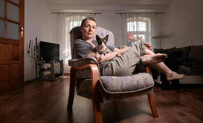 Woman holding sphynx cat and smiling in bright home interior