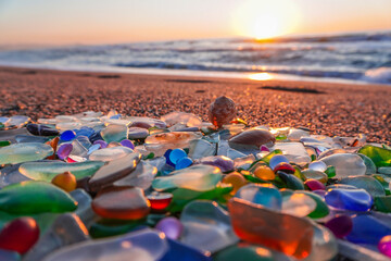 Colored sea glass with beach pebbles and shells in the mediterranean coast and in the background...