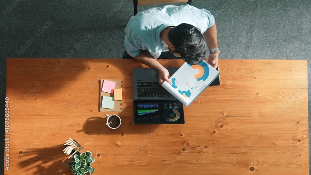 Aufkleber Top aerial view of manager working on laptop while looking at data analysis. Leader compare financial statistic graph while making decision at meeting table with document scatter around. Convocation.