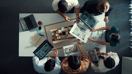 Top down view of manager pointing at house model and explain building design. Aerial view of...
