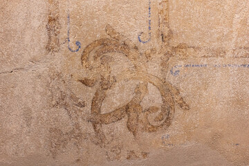 Aged plaster wall with faint fresco ornament and warm tone