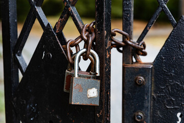 Rusty padlocks and chain securing an old metal gate close‑up