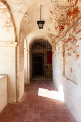 Arched cloister corridor with lantern leading to iron gate