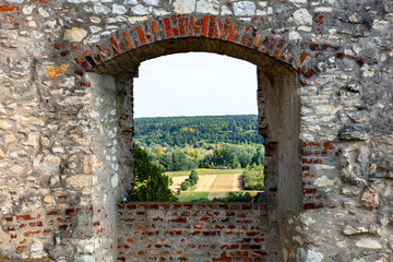 Scenic countryside framed by stone arch window in castle ruin