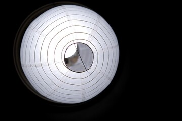 An oriental paper lamp hanging from the ceiling and glowing in the dark night 