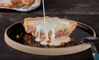Rhubarb pie with double cream being poured over it.