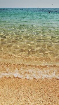 View from beach level on calm azul sea water and light waves approaching coastline.