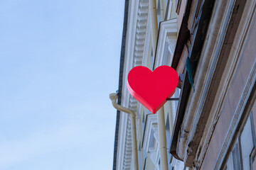 A model in the form of a red heart hangs on the wall of the building.