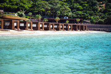 Wooden Loungers in a row on a beautiful beach with turquoise sea water
