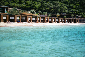 Wooden Loungers in a row on a beautiful beach with turquoise sea water