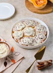 Step by step cooking pumpkin buns on light concrete background. Finished cinnabons in a round ceramic form. Recipes pumpkin, seasonal baking.
