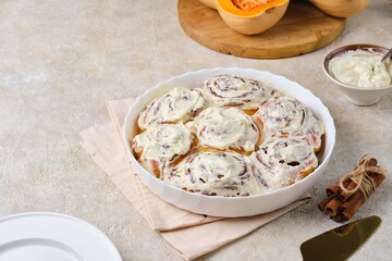 Step by step cooking pumpkin buns on light concrete background. Finished cinnabons in a round ceramic form. Recipes pumpkin, seasonal baking.