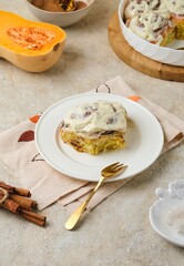 Step by step cooking pumpkin cinnabons on light concrete background. Ready bun with cream on white ceramic plate.