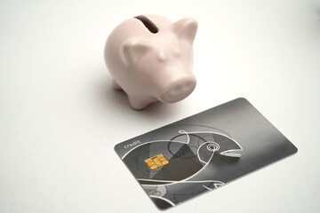 Pink piggy bank and black credit card placed on white background, representing saving money,...