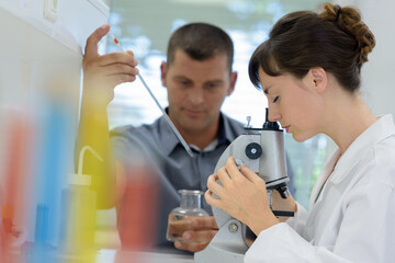 scientists in laboratory using microscope and pipette