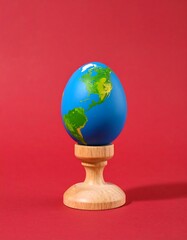 Painted Earth egg on wooden pedestal