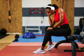 Naklejka premium Tired black woman resting after fitness training in gym