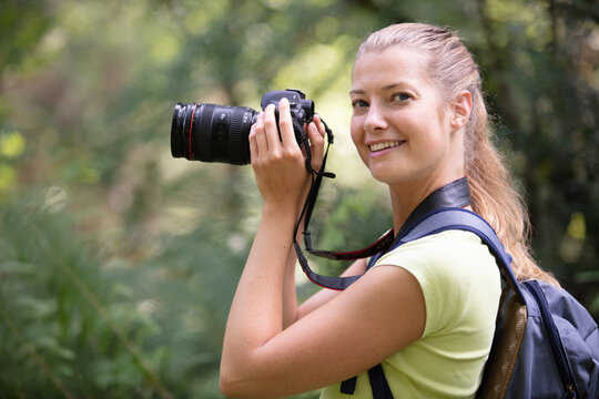 portrait of female photographer holding camera in the countryside