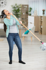 happy woman with mop cleaning floor and singing at home