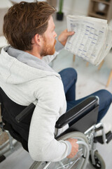 adult man in wheelchai reading newspaper