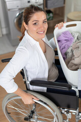 happy woman in wheelchair doing the laundry at home