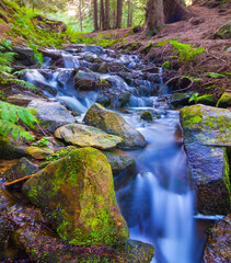 waterfall on small mountain brook rushing through canyon over a stones