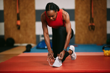 Black woman tying shoelaces getting ready for fitness training