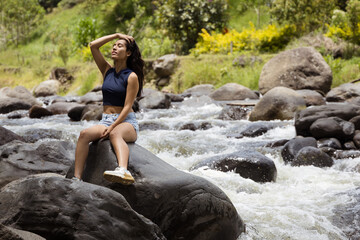 Portrait of a Cheerful Woman on a Rock in the Wilderness