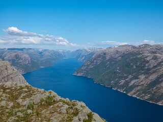 Fototapeta premium An awe-inspiring high-angle perspective from the Preikestolen trail captures the majestic Lysefjord, its blue water creating a contrast with the surrounding rugged mountains in Rogaland, Norway