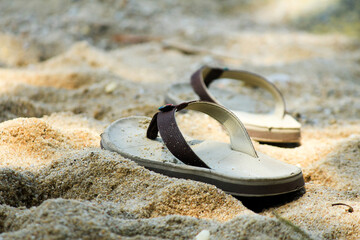 Pair of homemade sandals left on beach sand – concept of travel, solitude, and summer freedom.