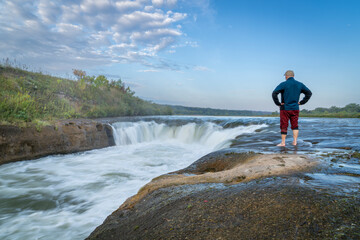 lonely man contemplating the Norden Chute on Niobrara River in Nebraska, late summer sunrise  scenery